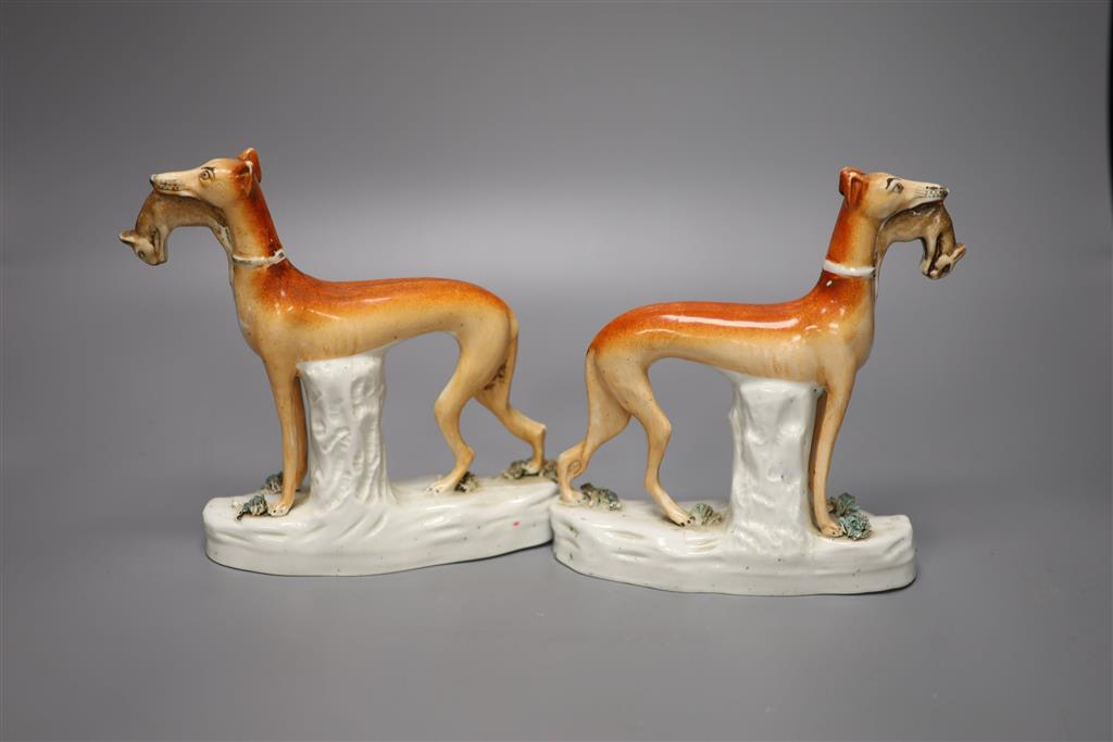 A pair of 19th century Staffordshire pottery greyhound figures, each with prey, 19cm high, 16.5cm long